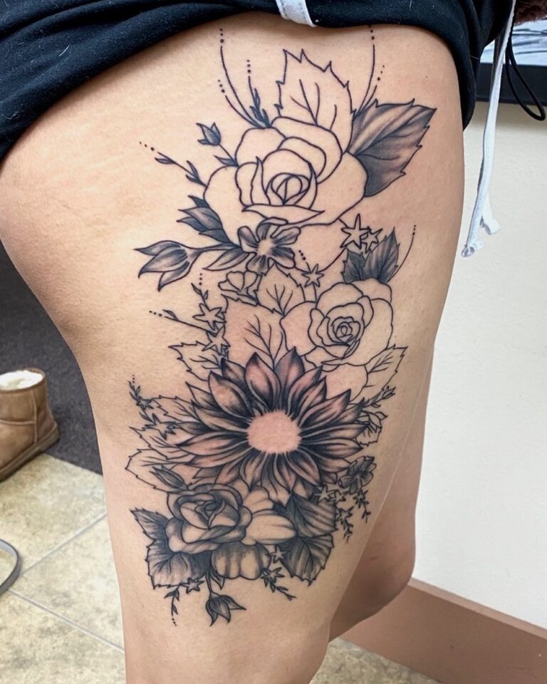 Floral tattoo design featuring roses, sunflowers, and leaves on a thigh, showcasing intricate line work and shading.