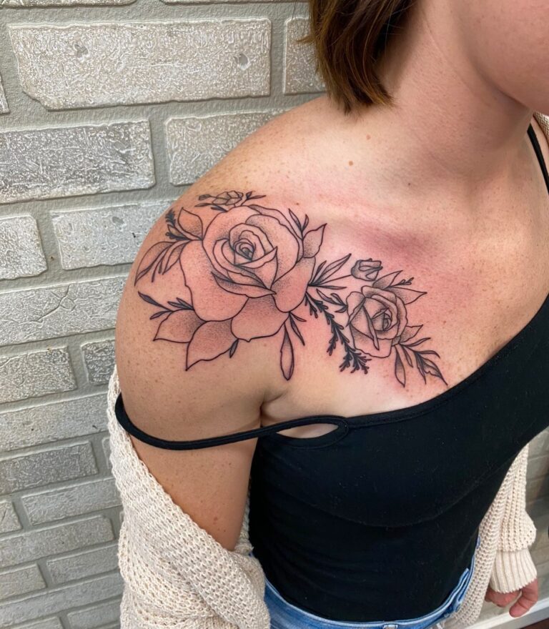 A detailed black line tattoo of roses and leaves adorns a woman's shoulder, showcasing floral artistry.