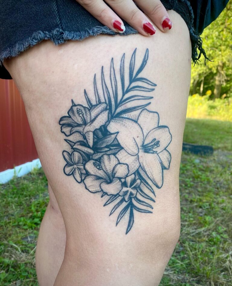A detailed black and gray floral tattoo featuring lilies and other flowers on a person's thigh.