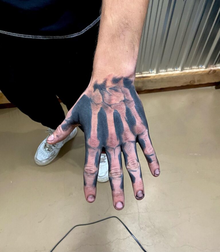 A hand with a realistic skeleton tattoo design, showcasing intricate details on the palm and fingers.