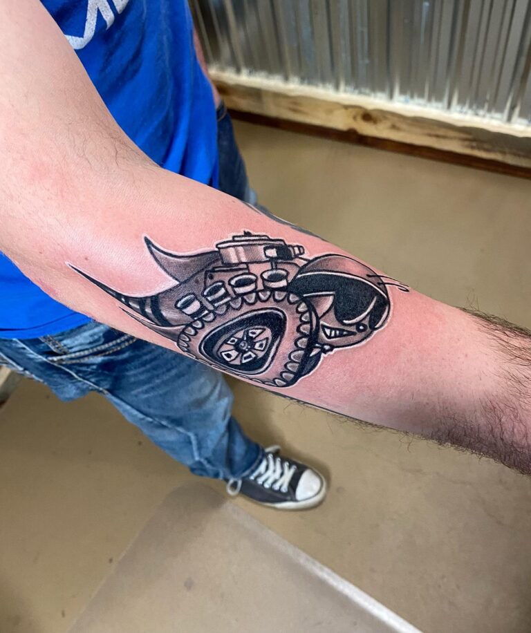 A detailed black tattoo of a stylized skull and gear on a person's forearm, showcasing intricate design elements.