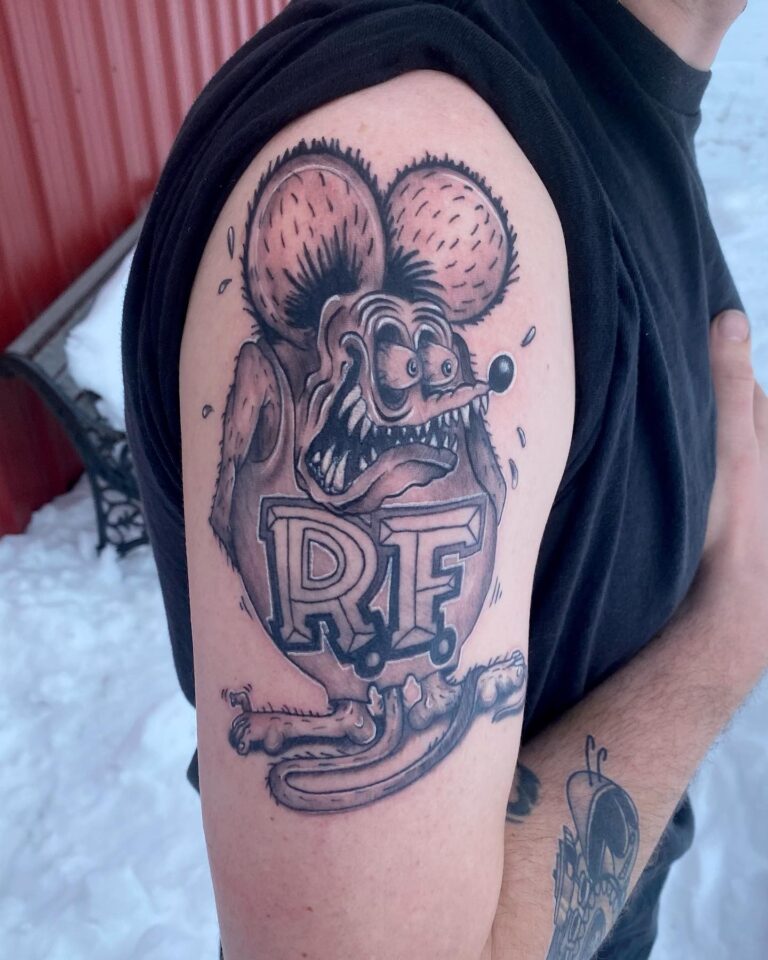 Tattoo featuring a grotesque cartoon mouse with exaggerated features and the letters "RF" on the arm.
