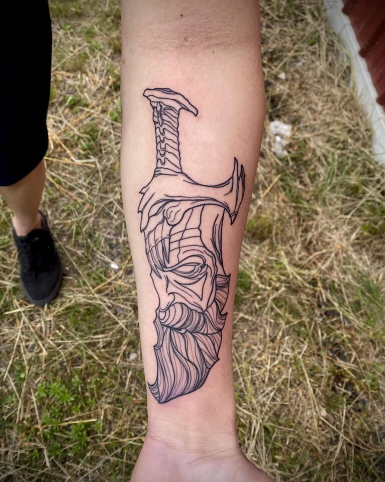 A detailed line art tattoo of a sword intertwined with a bearded face on a person's forearm.