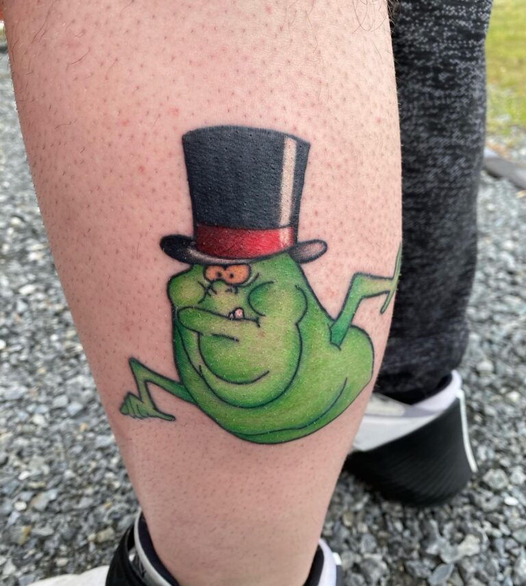 A vibrant tattoo of a green ghost wearing a top hat, showcasing a playful and whimsical design on a person's leg.