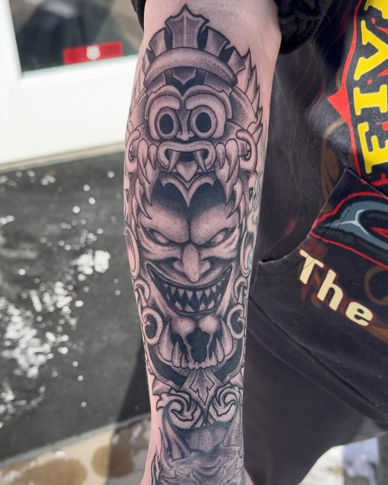 Detailed black and gray tattoo of a fierce, mythical creature on a person's forearm, showcasing intricate designs.
