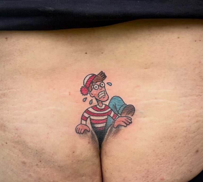 Tattoo of a cartoon character resembling Waldo, appearing to emerge from a person's lower back.